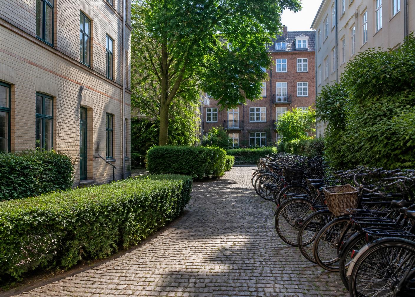 Grøn gård med klippede hække mellem københavnske ejendomme